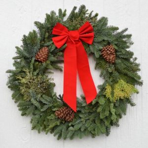 large christmas wreath with green bough, yellow cedar, blue juniper berries, three pinecones and red bow