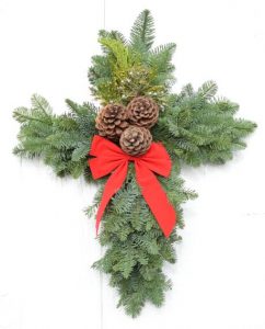 Cross shaped wreath with red bow and pinecones in the middle